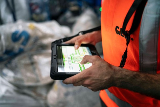 Operario de GLS utilizando una tablet para clasificar paquetes en un centro logístico de almacenamiento y distribución